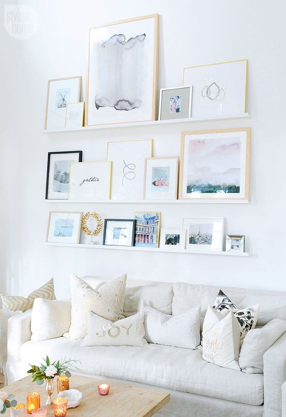 I love how all the images on this gallery "wall" are propped up on shelves! The artwork and different size frames really makes this a great focal piece in the room.