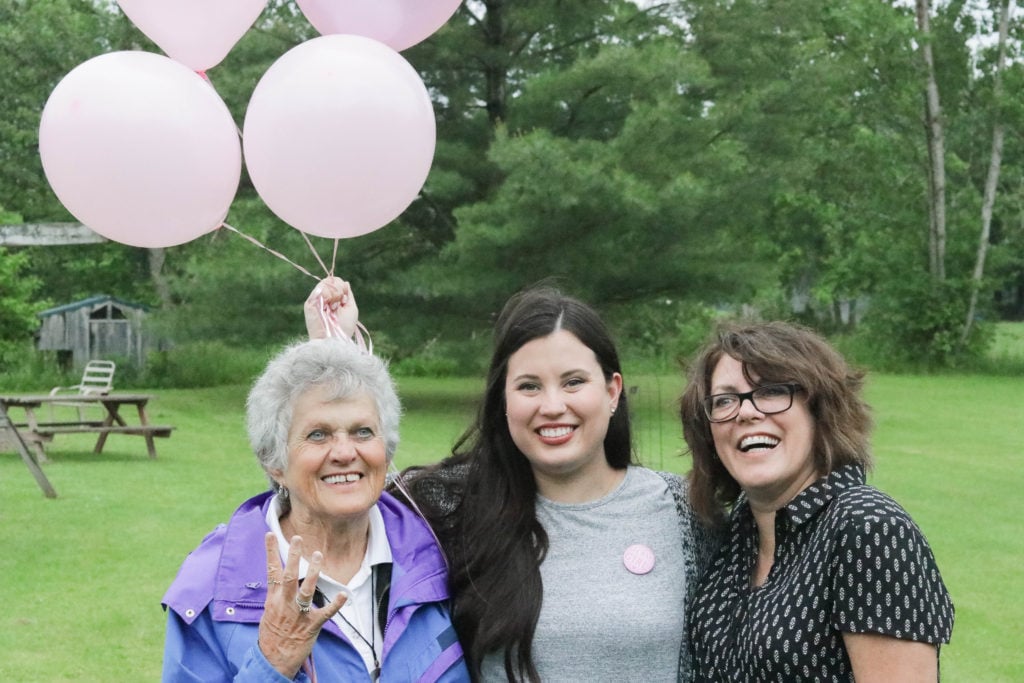 Gender Reveal Party - three generations of women holding pink balloons, excited to have the fourth girl to be added.