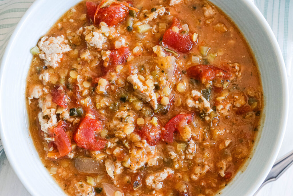 Blue bowl of curry lentil and turkey stew cooked in a slow cooker. Hearty and warm, protein packed, warm curried tomato based stew. Gluten Free and Dairy Free. || Nikki's Plate