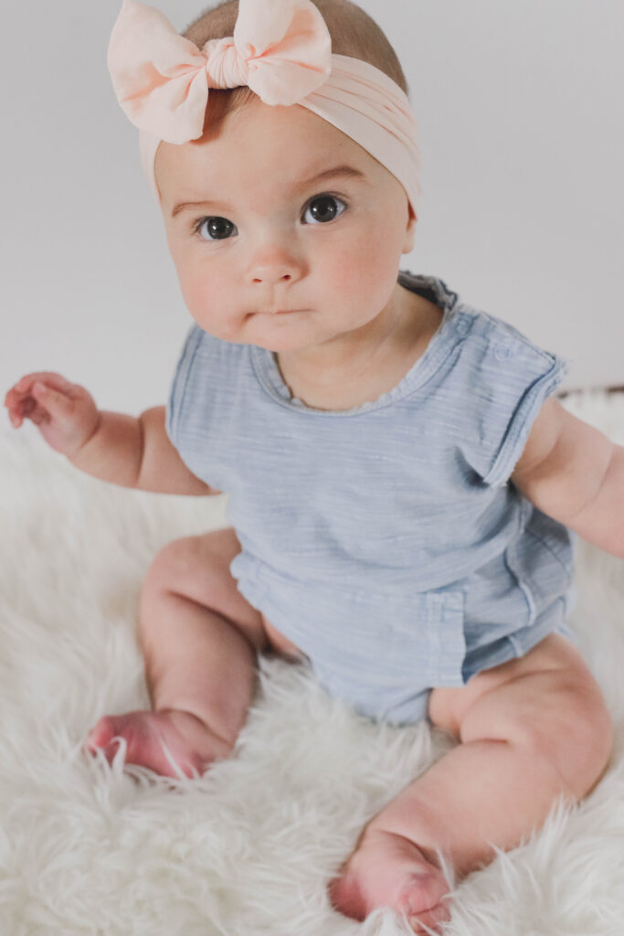 6 month old schedule - day in the life of a baby - infant girl with blue onesie and pink headband on. Baby photography