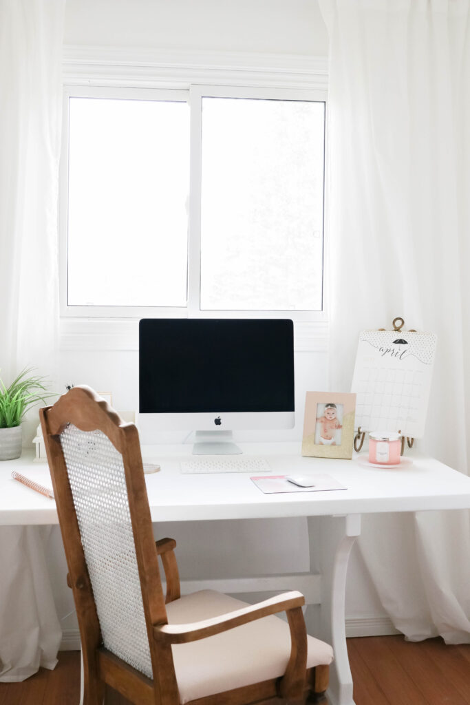 Girly White office with vintage wood chair, iMac computer, greenery, tall calendar, white vintage chair, daughter framed picture, white linen drapes || Nikki's Plate