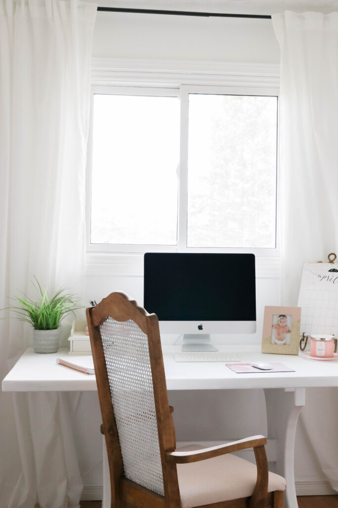 Girly White office with vintage wood chair, iMac computer, greenery, tall calendar, white vintage chair, daughter framed picture, white linen drapes || Nikki's Plate