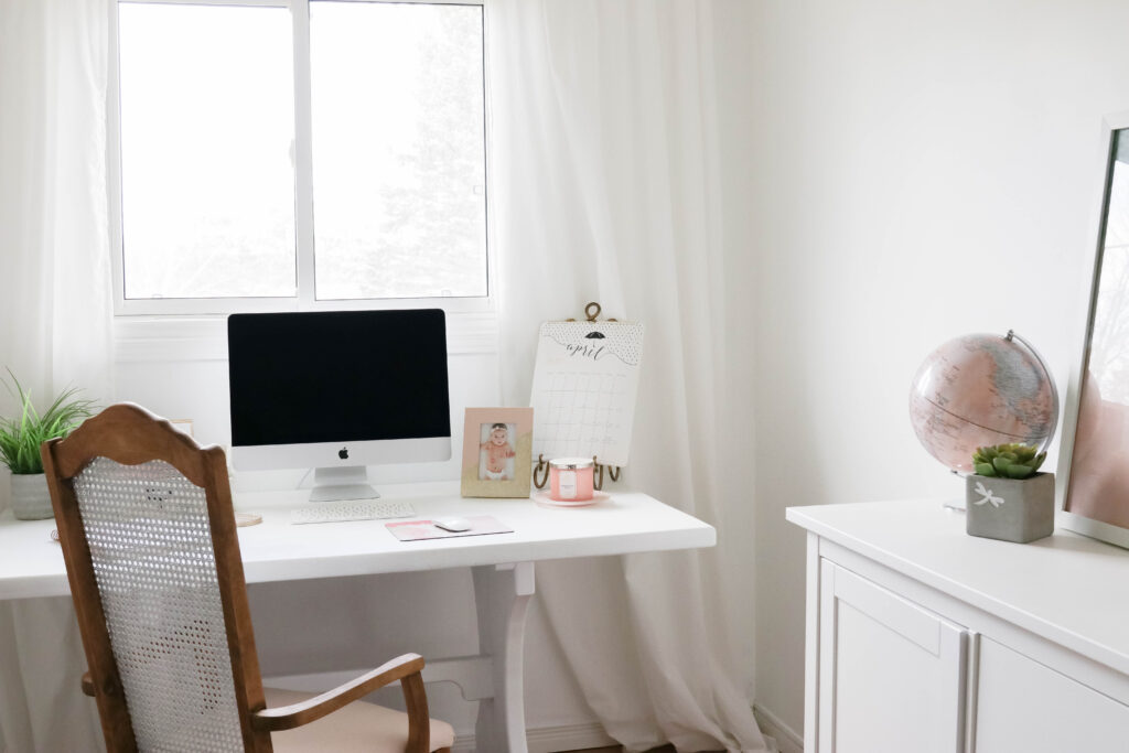 Girly White office with vintage wood chair, iMac computer, greenery, tall calendar, white vintage chair, daughter framed picture, white linen drapes || Nikki's Plate