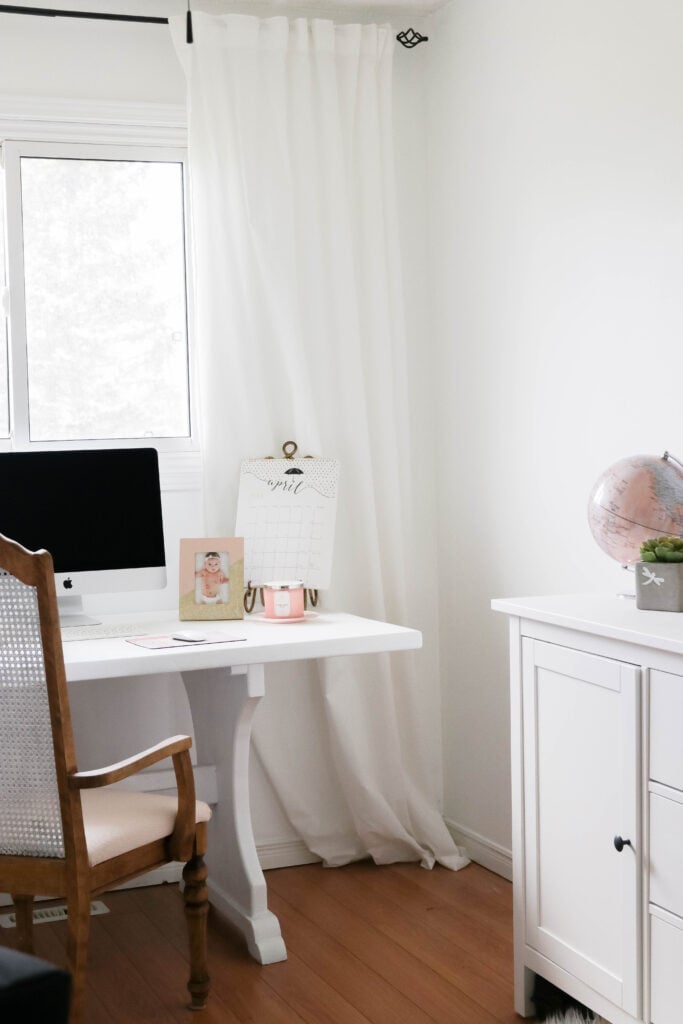 Girly White office with vintage wood chair, iMac computer, greenery, tall calendar, white vintage chair, daughter framed picture, white linen drapes || Nikki's Plate