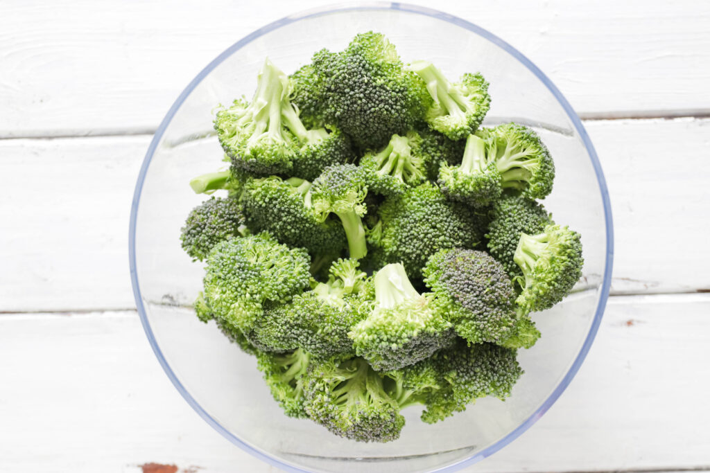 Bowl of green broccoli - Crispy Broccoli with Vegan Cheese Sauce; dairy and gluten free side dish for your vegan dinner! A nut free cheese sauce that you will love smothered on your blackened broccoli!