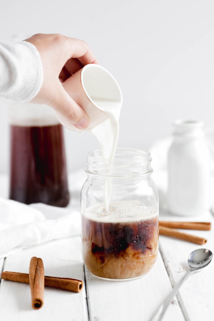 Overnight Cinnamon Cold Brew Coffee - pouring almond milk into cold coffee with ice 