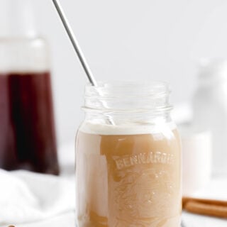 Overnight Cinnamon Cold Brew Coffee - mason jar full of cold coffee beverage with stainless steel straw over ice. Almond milk making it a vegan beverage