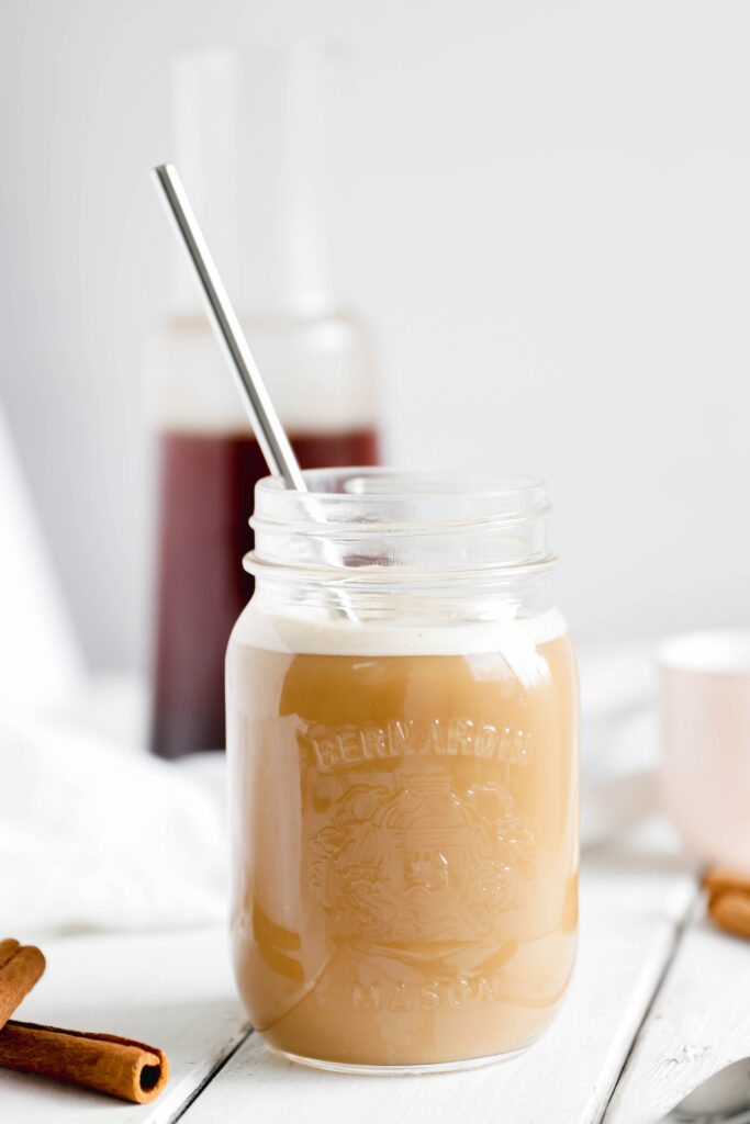 Cinnamon cold brew coffee in a mason jar with straw, almond milk in coffee