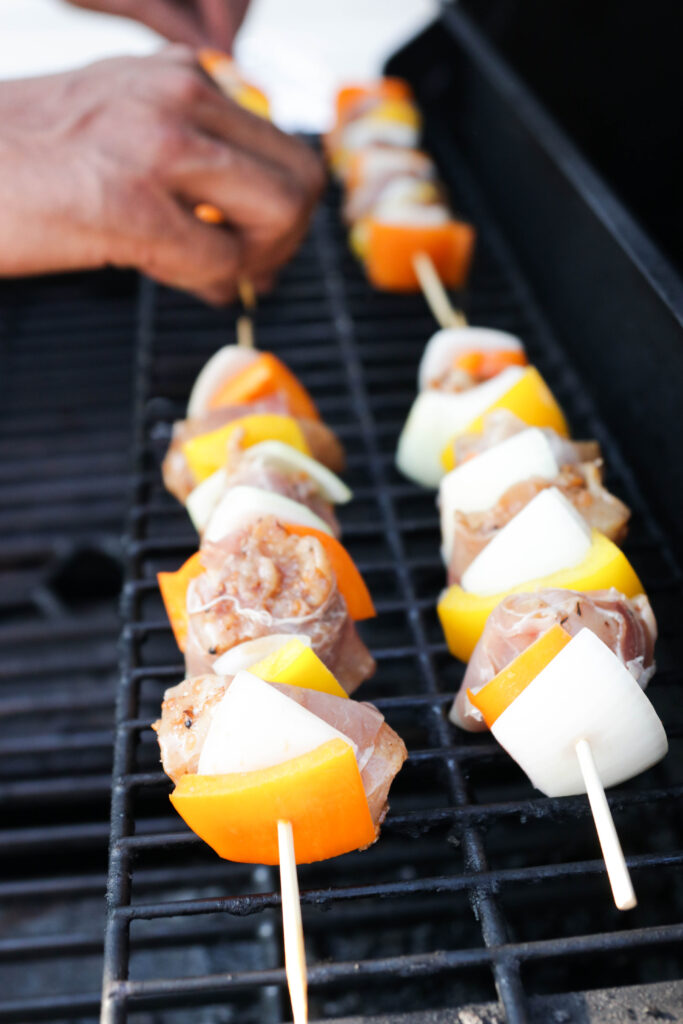 Adding skewers to the BBQ to be grilled