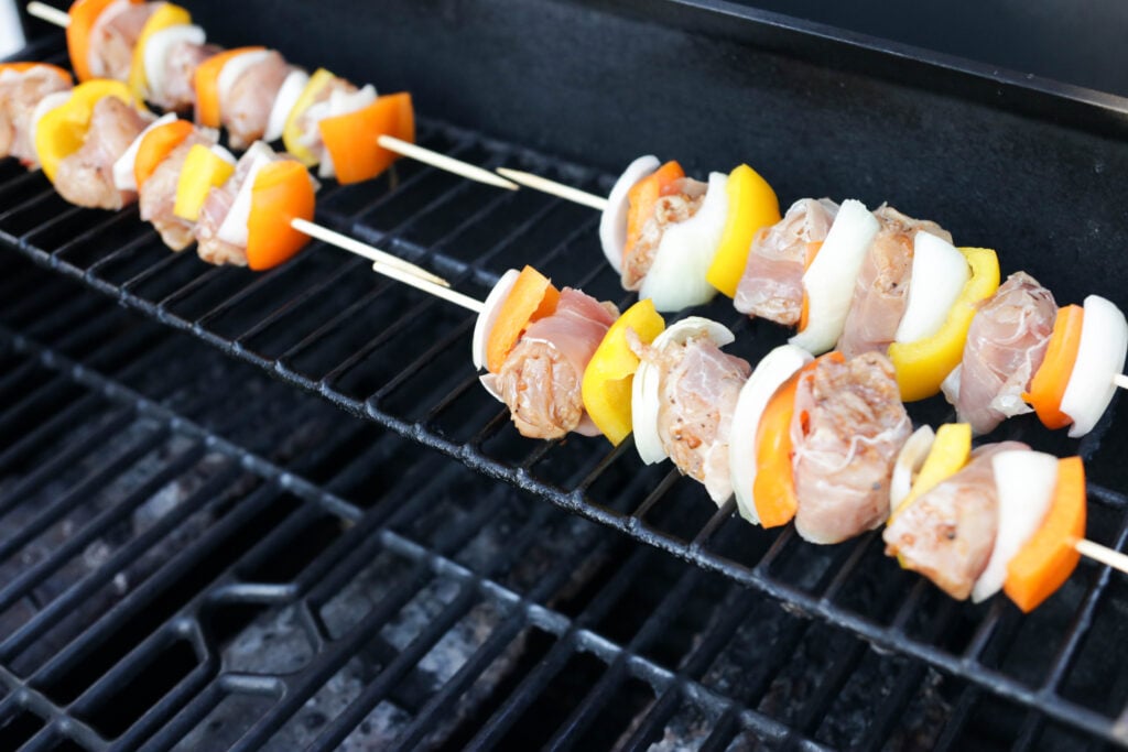 Grilling prosciutto wrapped chicken skewers on the BBQ