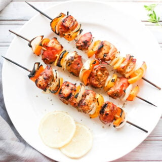 This Prosciutto Wrapped Chicken Skewers recipe is a quick and easy BBQ dinner that is bursting with salty goodness and juice peppers and onions. || Nikki's Plate