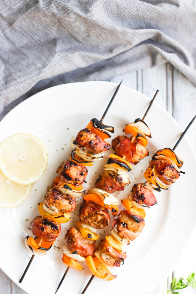 This Prosciutto Wrapped Chicken Skewers recipe is a quick and easy BBQ dinner that is bursting with salty goodness and juice peppers and onions. || Nikki's Plate