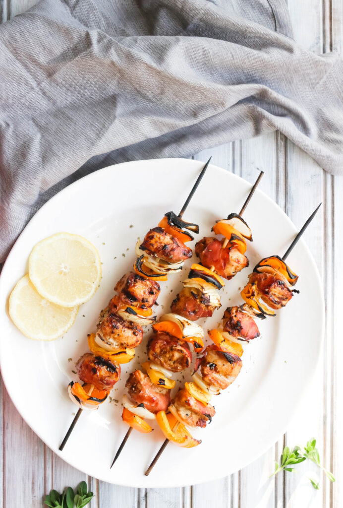 This Prosciutto Wrapped Chicken Skewers recipe is a quick and easy BBQ dinner that is bursting with salty goodness and juice peppers and onions. || Nikki's Plate