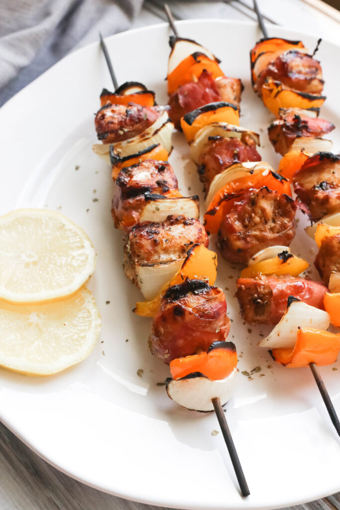 This Prosciutto Wrapped Chicken Skewers recipe is a quick and easy BBQ dinner that is bursting with salty goodness and juice peppers and onions. || Nikki's Plate