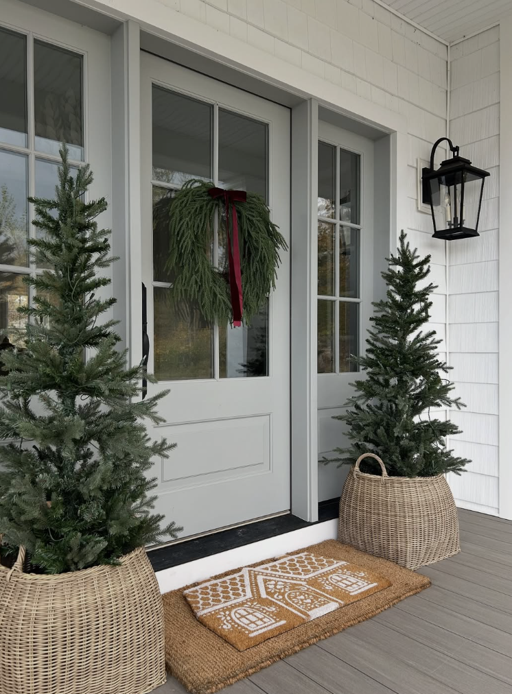 Classic winter front porch decor with potted evergreen trees, a minimalist winter wreath, and a neutral doormat
