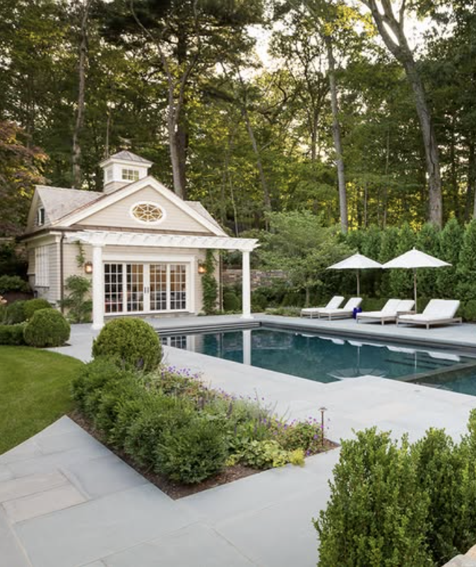 classic shingle style pool house with white columns and backyard swimming pool