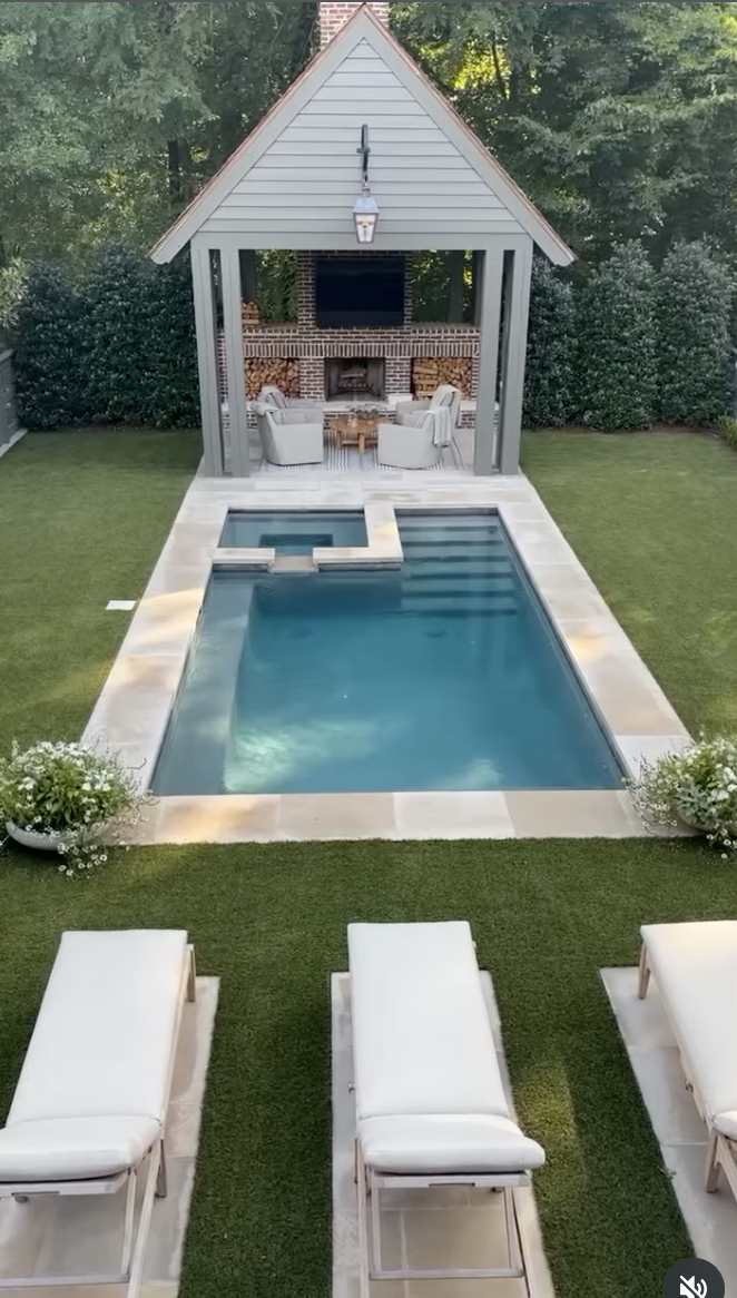 small gable style pool house with brick fireplace and backyard swimming pool