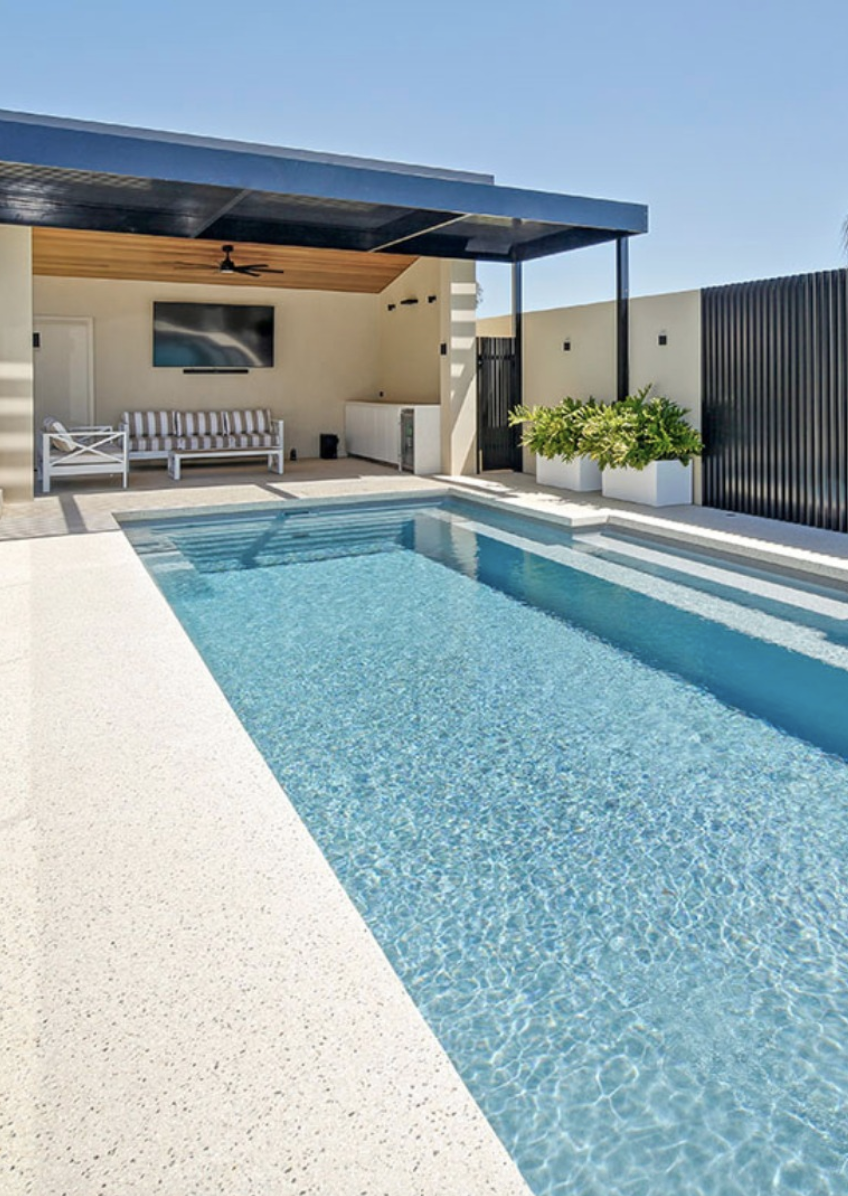 contemporary pool house with flat roof, covered patio lounge, and modern rectangular swimming pool