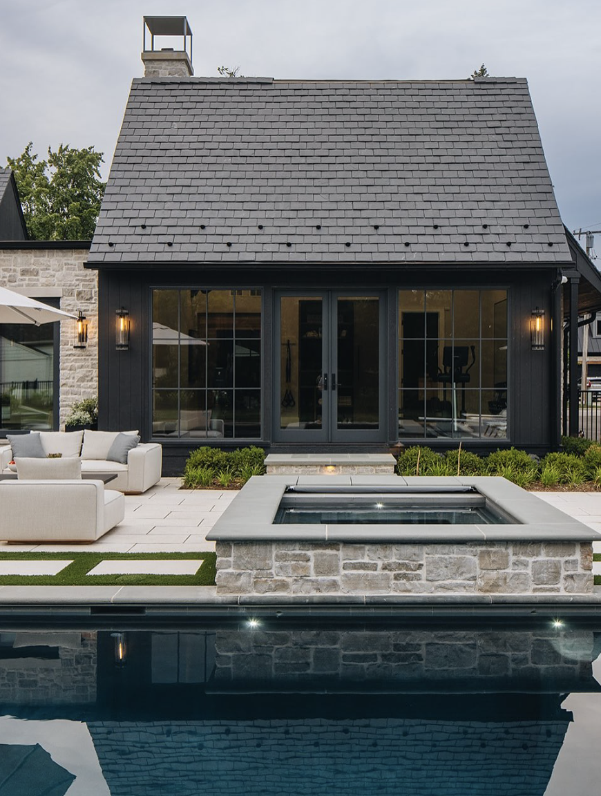 dark modern farmhouse pool house with large black windows and backyard swimming pool