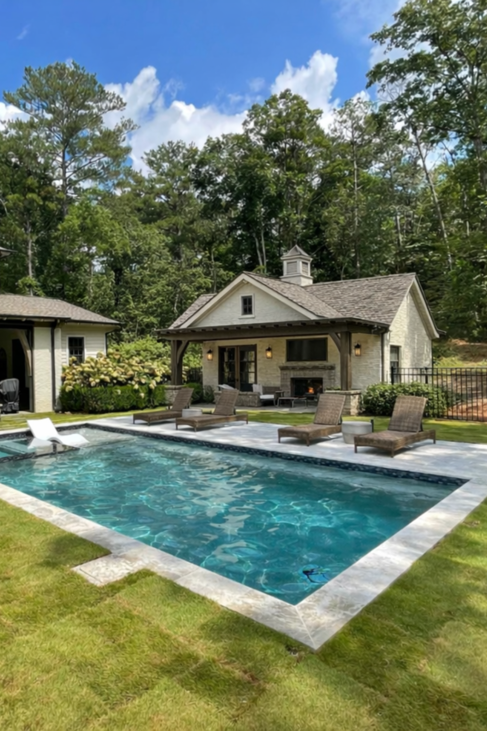 farmhouse style backyard pool house with covered patio, stone fireplace, and rectangular swimming pool