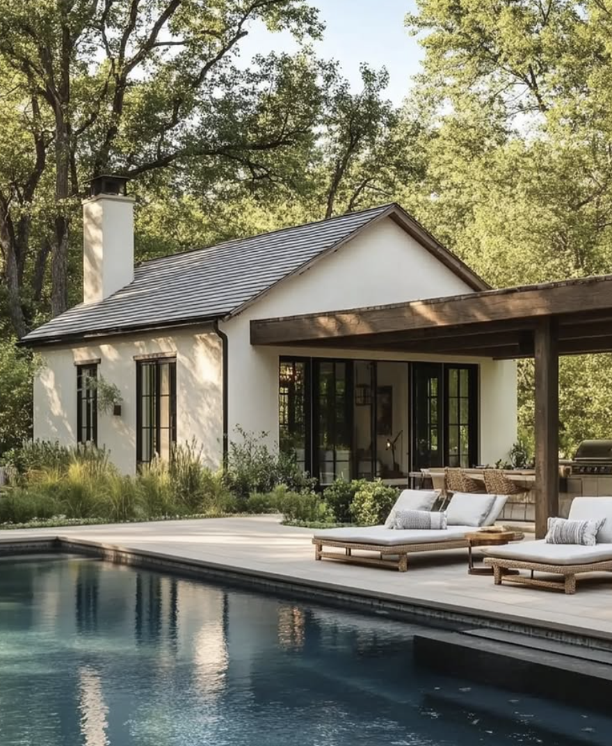 modern white farmhouse pool house with black-framed windows, wood beam pergola, and lounge chairs beside a sleek rectangular pool