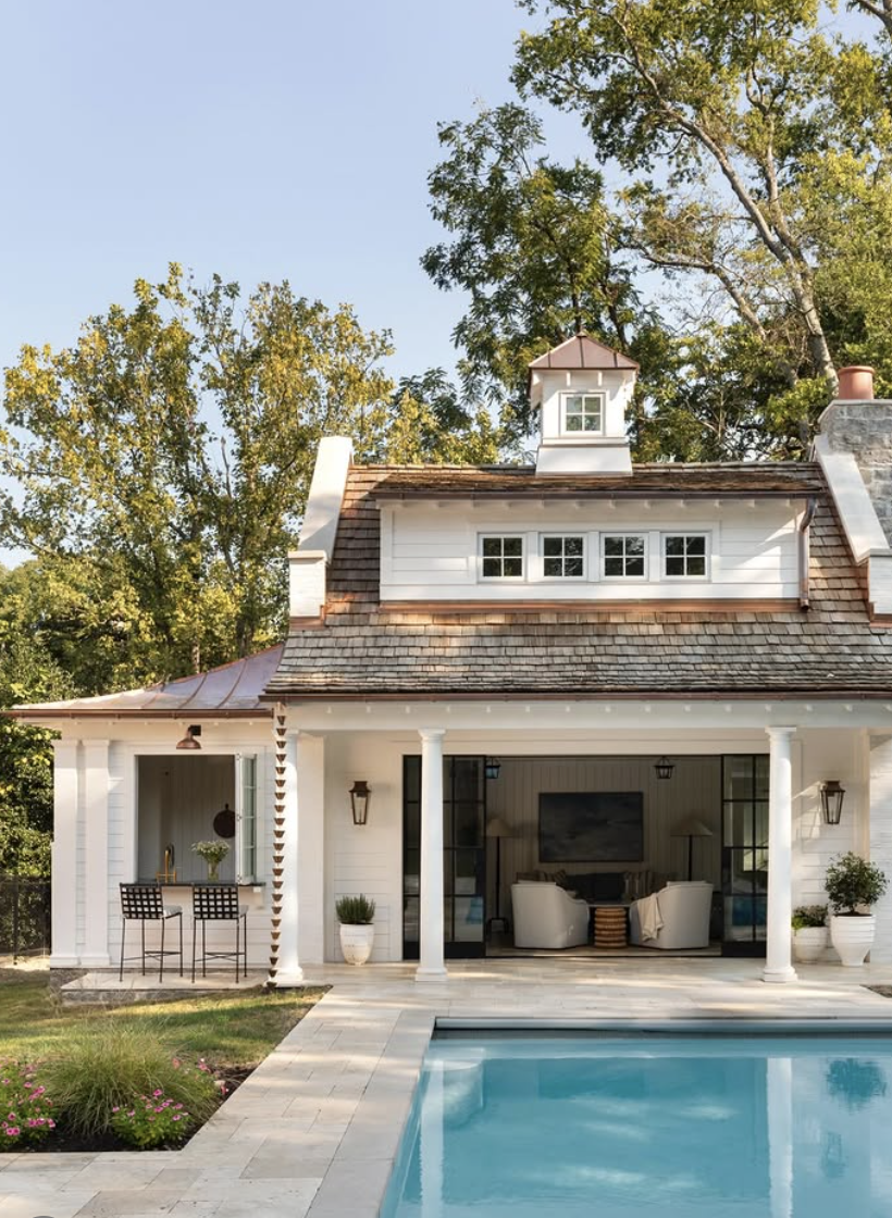 white cedar shake pool house with cupola and covered patio beside backyard pool