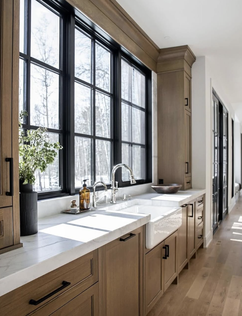 white oak kitchen with black windows, farmhouse sink, and natural wood cabinets