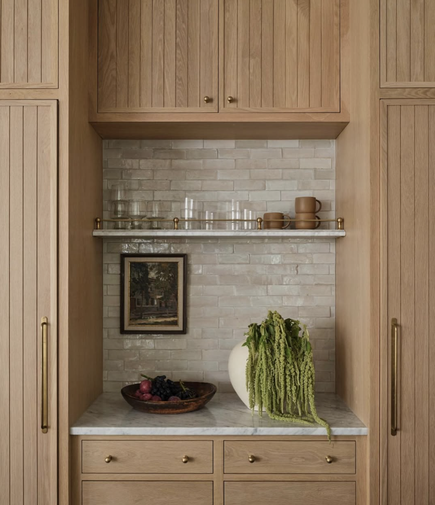 white oak kitchen with glass front cabinets, marble countertops, and warm wood cabinetry