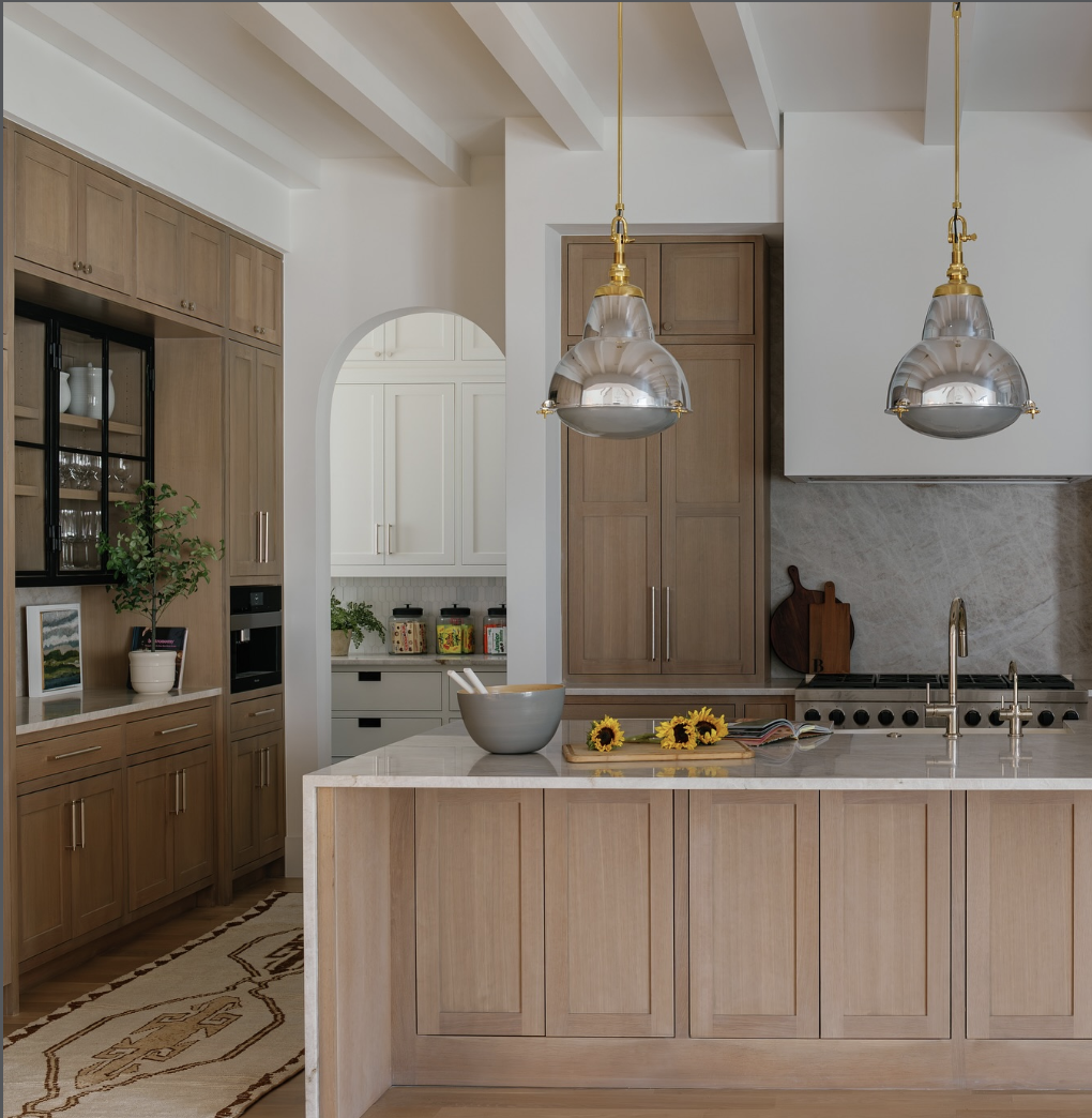 white oak kitchen with marble island, glass pendant lighting, and warm wood cabinets