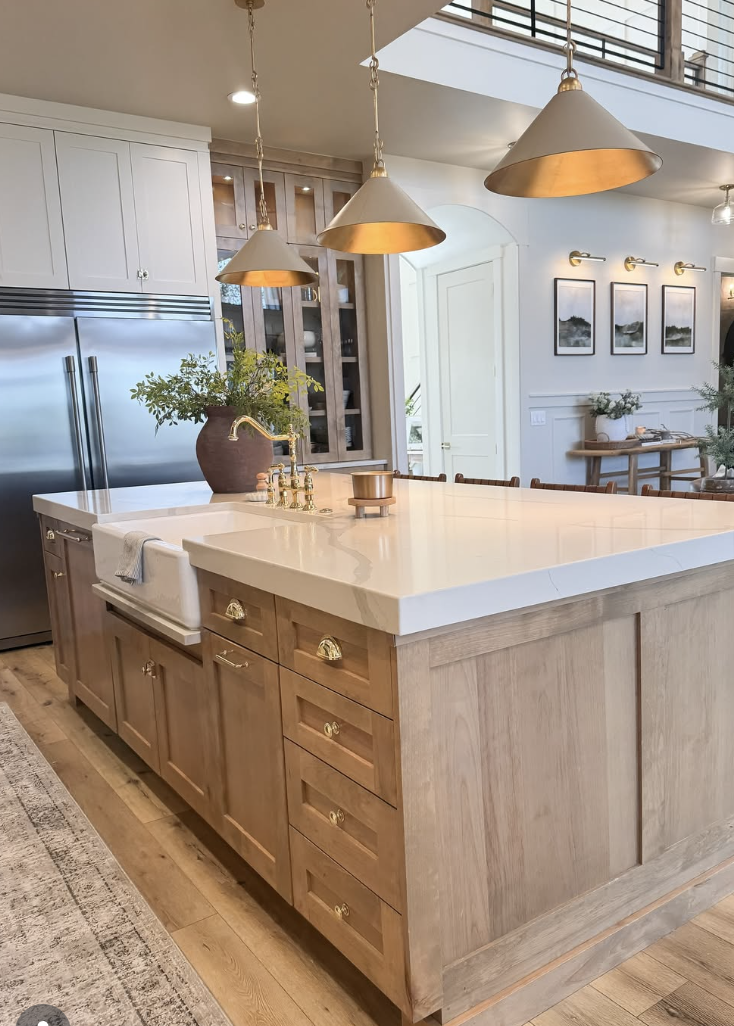 white oak kitchen with large island, brass pendant lights, and farmhouse sink