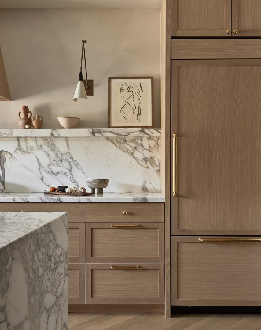 white oak kitchen with marble backsplash, brass hardware, and light wood cabinets