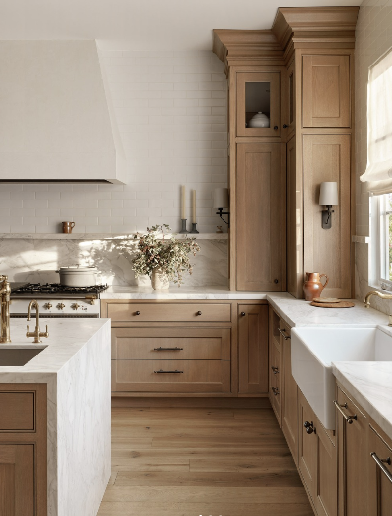 white oak kitchen with marble countertops, brass faucet, and warm wood cabinets