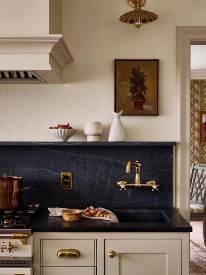 This beautiful space highlights how soapstone countertops can create a seamless, high-end look when extended into a full backsplash. The rich, dark tones paired with warm brass fixtures add depth and elegance, while the soft cabinetry keeps everything feeling balanced. It's a timeless design that feels both classic and elevated.