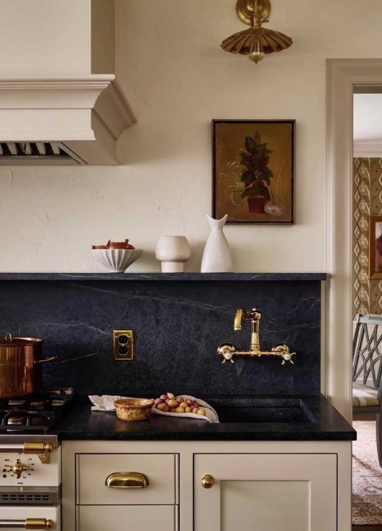 kitchen with soapstone countertops and backsplash, brass faucet, and warm neutral cabinets