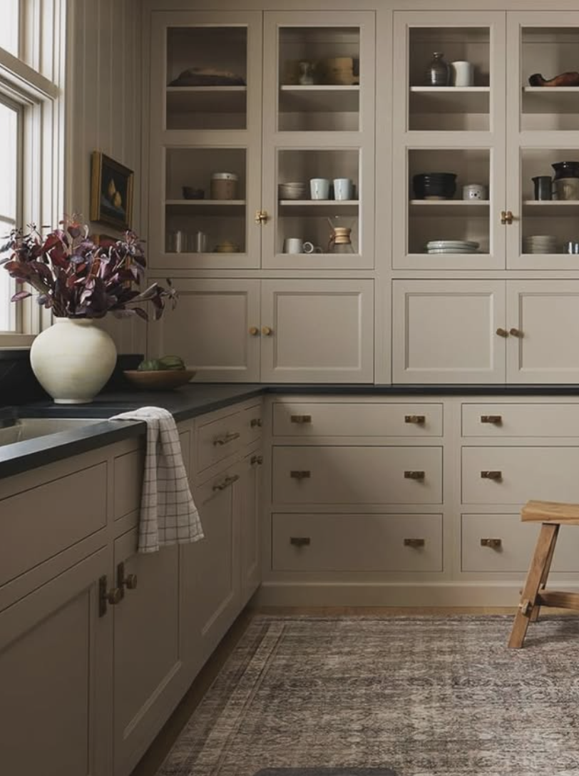 neutral kitchen with soapstone countertops, glass cabinets, and warm beige tones