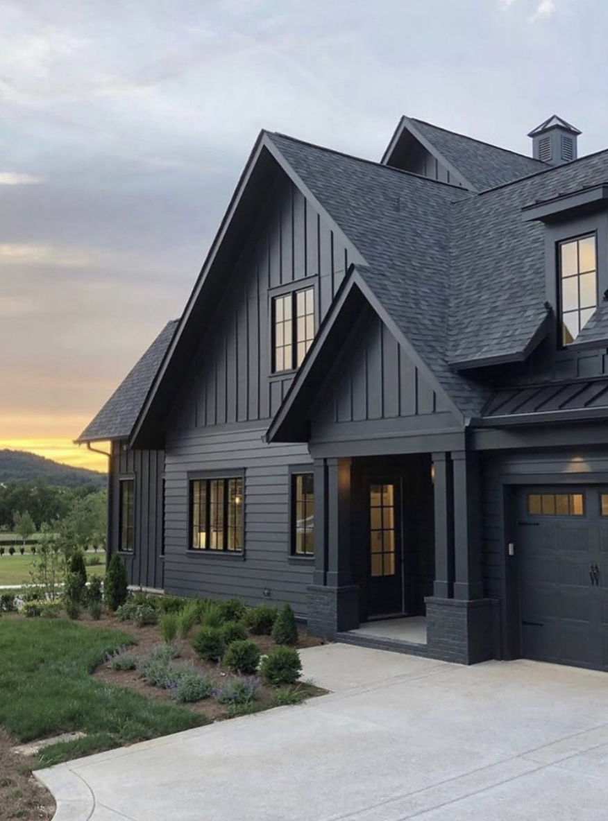Landscaping ideas for front of house featuring a dark farmhouse exterior with simple foundation shrubs and modern curb appeal.