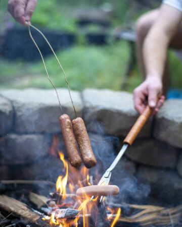 Hot dogs being roasted over a camp fire - 10 Easy Campfire Recipes (Be the Master of Campfire Cooking); Here are 10 campfire cooking recipes to try this summer!