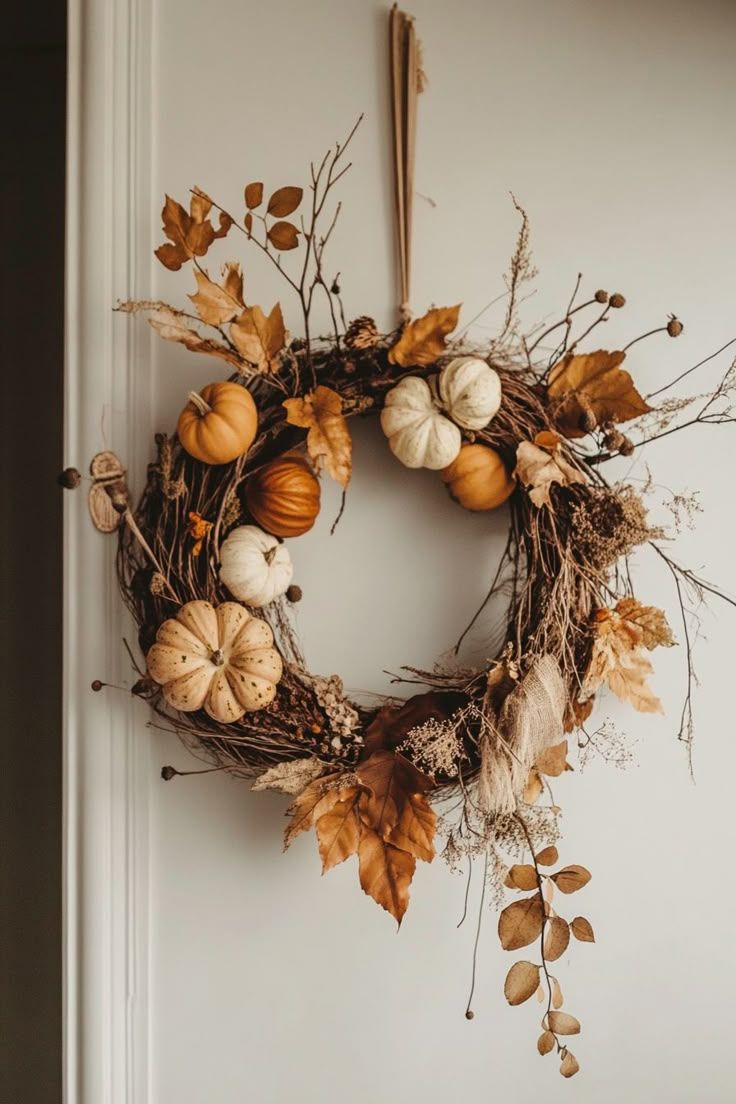 Handmade DIY fall wreath with mini pumpkins, dried leaves, and twigs in warm autumn tones, perfect for budget-friendly seasonal decorating.