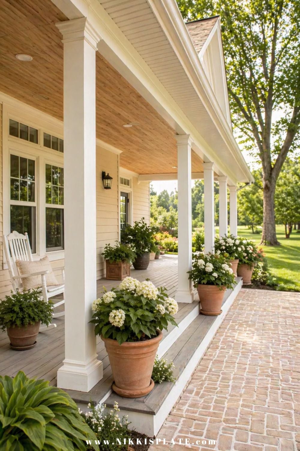 front porch planter ideas with white hydrangeas in terracotta pots along a columned porch