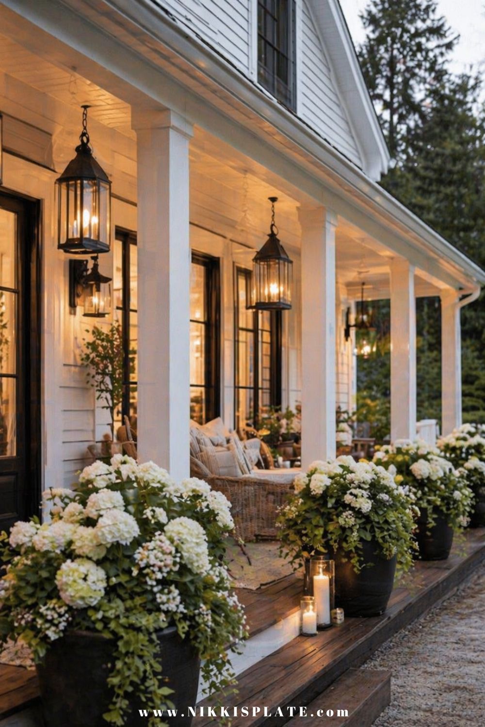 Front porch planter ideas with large black pots filled with hydrangeas and soft lighting on a welcoming front porch at dusk