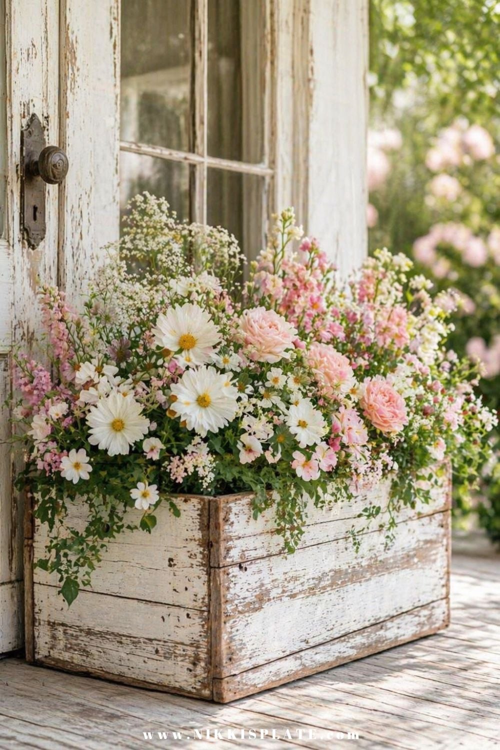 Front porch planter ideas with a rustic wooden box filled with pink and white flowers and trailing greenery
