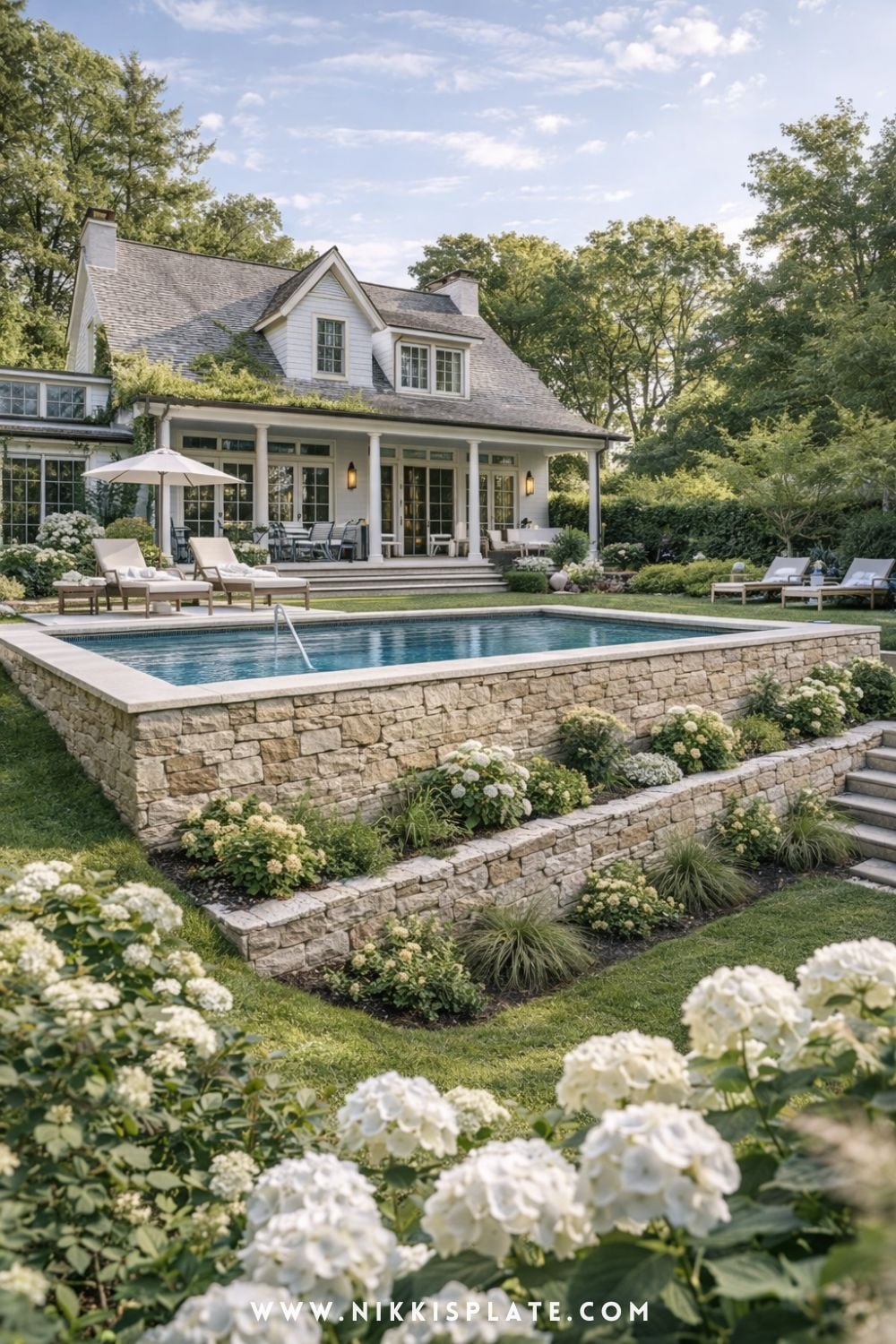 Elegant Farmhouse Hillside Pool with Tiered Retaining Walls - Hillside pool with retaining walls and tiered stone landscaping in a farmhouse-style sloped backyard
