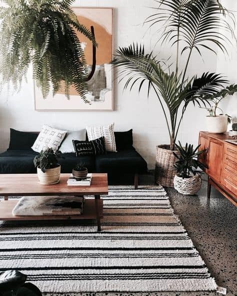 20 Beautiful Black Couch Living Room Ideas; black sofas in bohemian living rooms with striped rug and plants