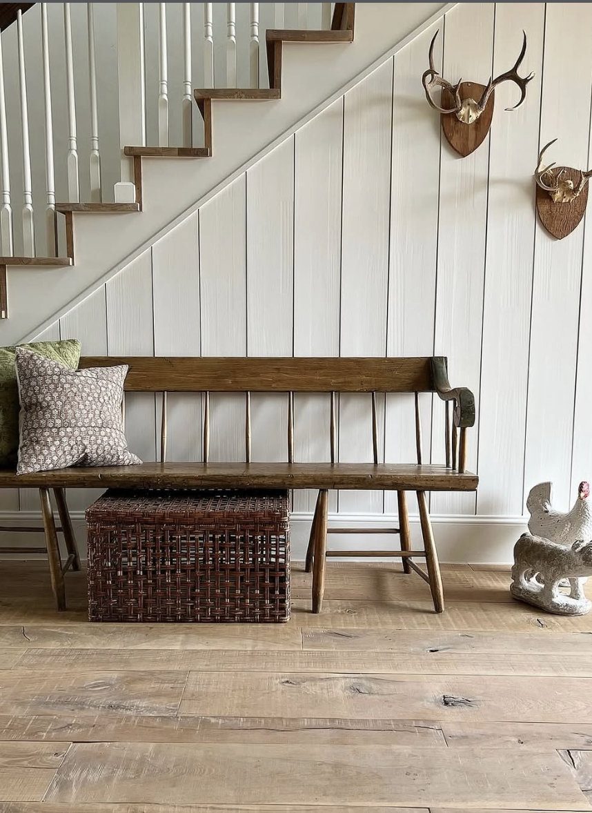 natural wood flooring in cozy farmhouse entryway with bench and shiplap wall