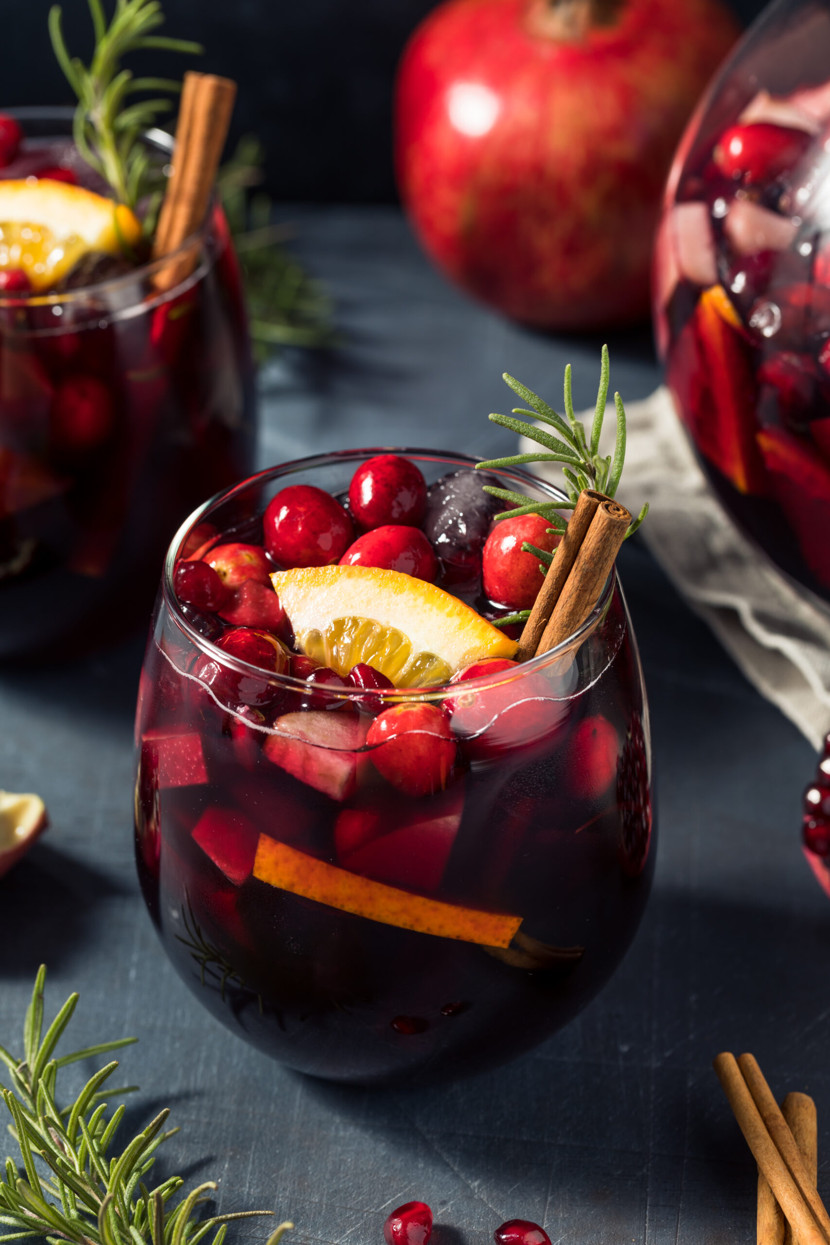 Red Christmas Sangria Recipe; made with red wine, brandy cranberry pomegranate juice, sparkling apple cider and fruit. Topped with cinnamon sticks and rosemary to garnish
