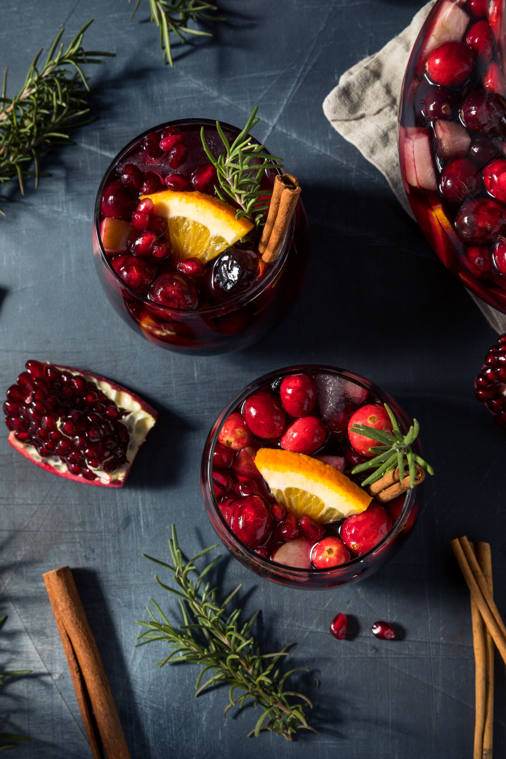 Red Christmas Sangria Recipe; made with red wine, brandy cranberry pomegranate juice, sparkling apple cider and fruit. Topped with cinnamon sticks and rosemary to garnish