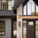 Dark farmhouse exterior with beige brick, black front door, grey siding