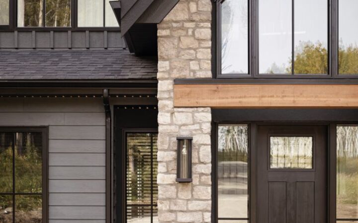 Dark farmhouse exterior with beige brick, black front door, grey siding