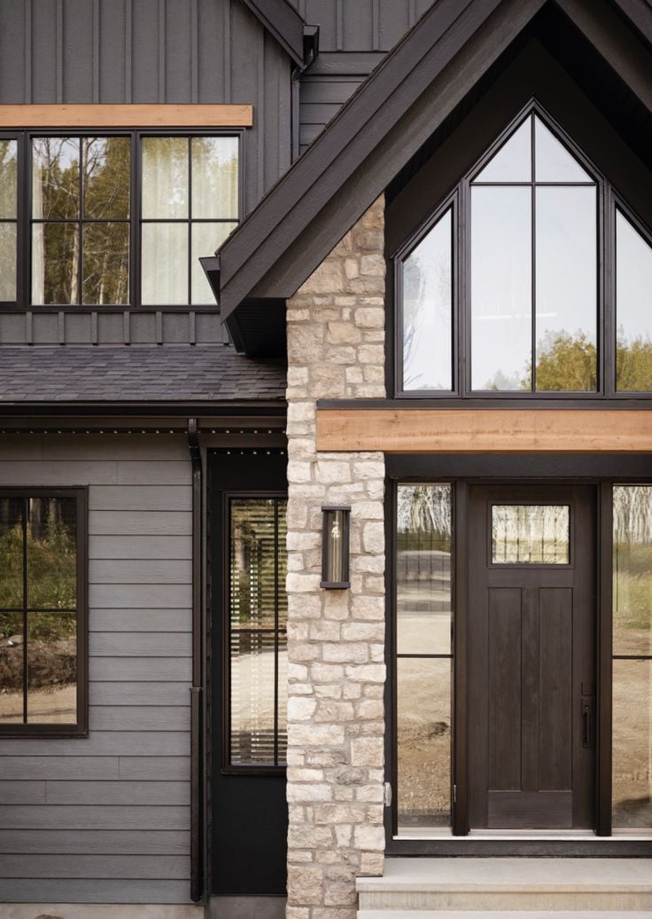 Dark farmhouse exterior with beige brick, black front door, grey siding