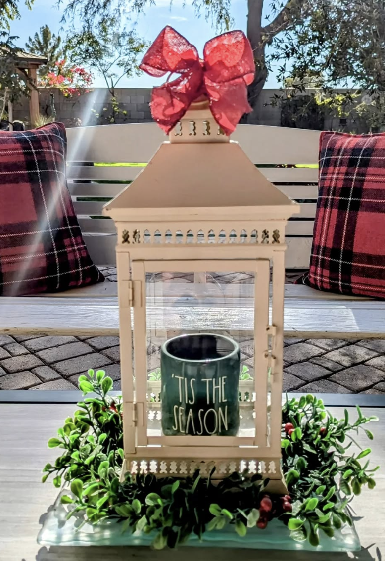 White lantern decorated with a red bow, holiday greenery, and a 